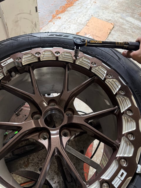Close-up of a dark metallic car wheel rim being measured with a digital caliper tool
