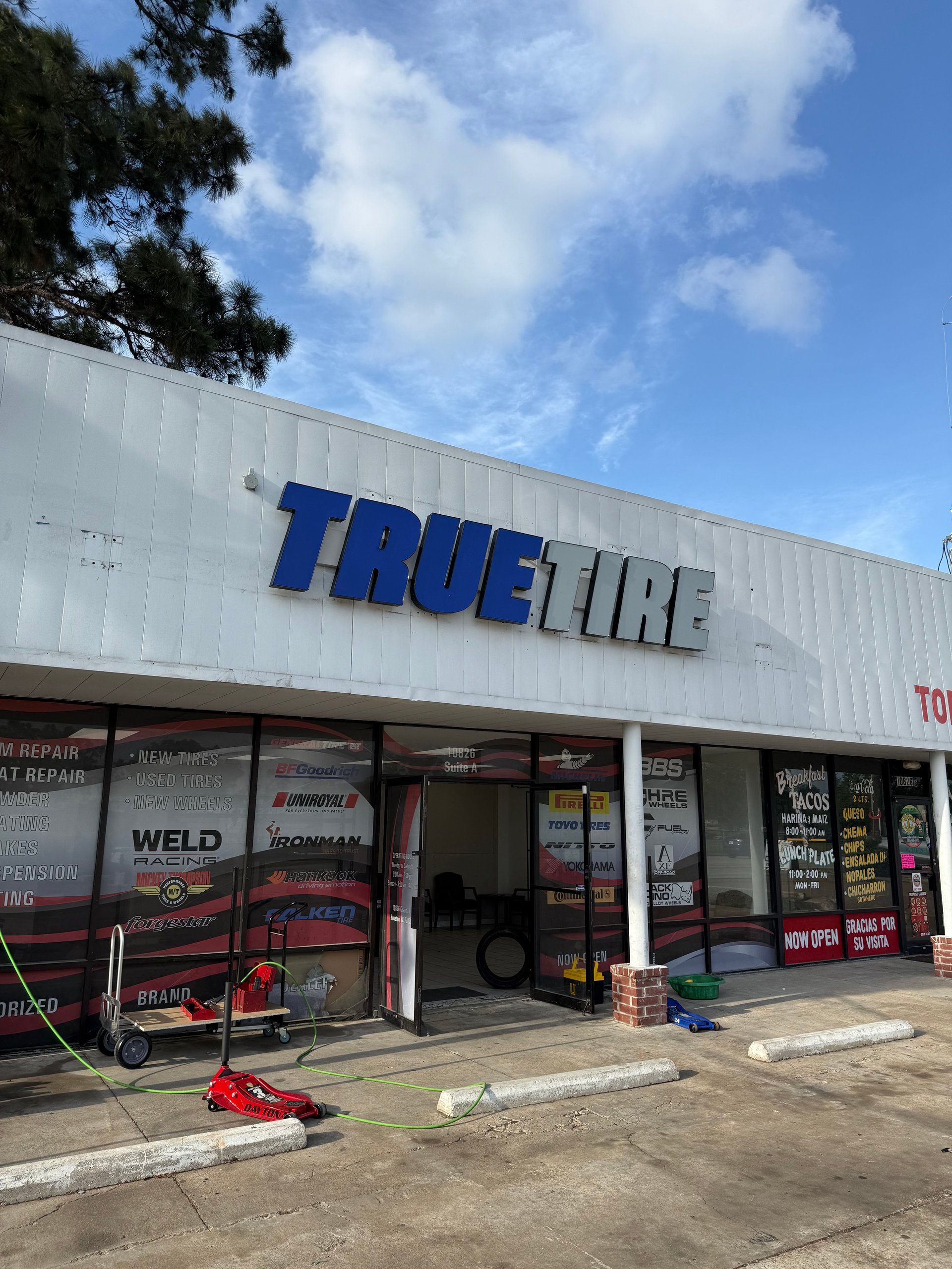 Exterior of True Tire auto repair shop with white metal building and blue signage